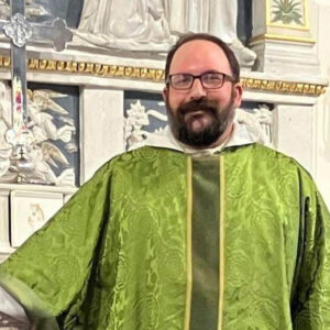picture of Father David Radzik in a green vestiment standing in front of the altar